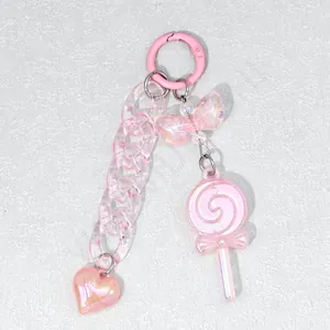 Pink acrylic phone charm detail with heart pendant, chain, and colorful ribbon bow
