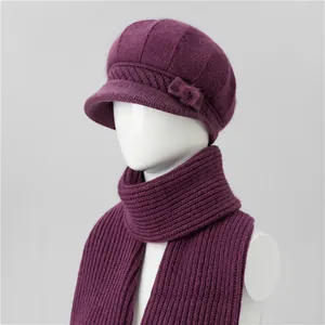 Dettaglio del set cappello e sciarpa in maglia viola con pompon e fiocco