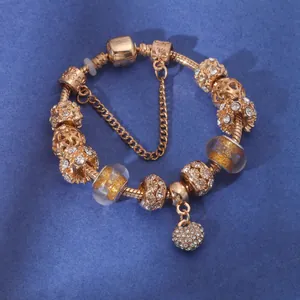 Detail of rose gold charm bracelet with crystal heart pendant and beads on blue background