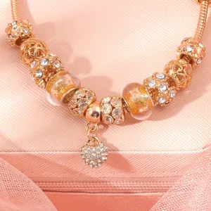 Macro view of rose gold snake chain bracelet with crystal heart charm and beads