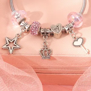 Close-up of a silver beaded charm bracelet with pink glass beads and crown star pendants
