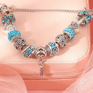 Detail of silver beaded bracelet with blue crystals and tassel on a pink velvet gift box