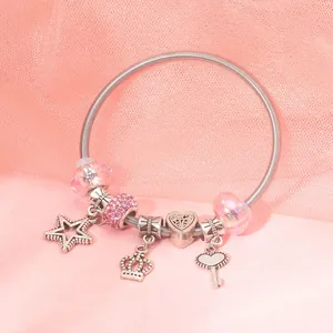 Detail of silver beaded bracelet featuring pink glass beads and a heart key charm