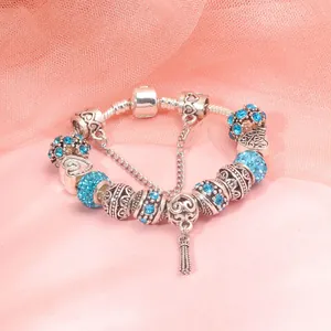 Detail of silver beaded bracelet featuring sky blue rhinestones and a delicate tassel charm