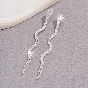 Dettaglio di orecchini a serpente in argento scintillante con lunghe nappe e strass