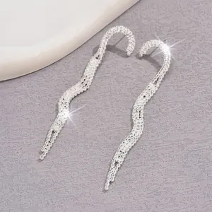 Dettaglio orecchini pendenti argento con strass scintillanti e design a onde mobili