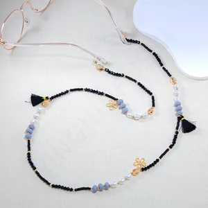 Detailed shot of beaded eyewear chain with pearls, gold floral charms and black tassels