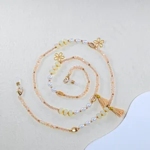 Detail of beaded glasses chain with pearls, gold flower charms, and champagne tassels