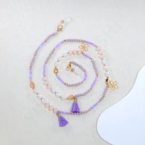 Detailed close-up of beaded eyewear chain with purple tassels and golden flowers