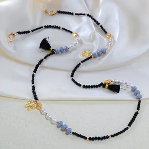 Detailed view of beaded eyeglass chain with pearls, gold heart charm, and black tassel
