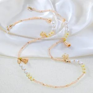Detail of beaded glasses chain with pearls, gold flowers and yellow tassels on silk