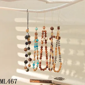 Detail of beaded mobile phone straps with wooden beads and turquoise on a wooden branch