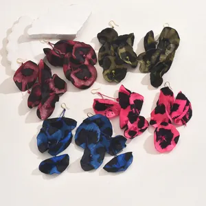 Detail of petal-shaped leopard print fabric earrings in burgundy, green, and blue