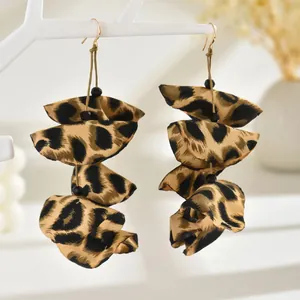 Close-up of leopard print fabric earrings with gold hooks and layered ruffle design