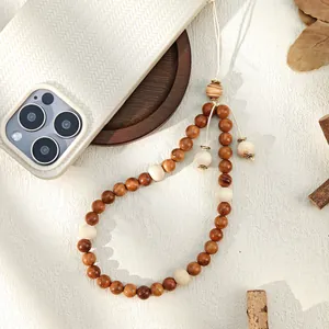 Detail of bohemian wooden beaded phone strap with natural brown and cream beads on textured case