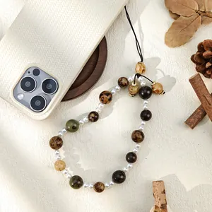 Close-up of wooden bead phone strap with white pearls on a woven texture phone case