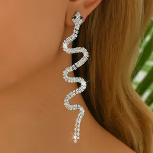 Detailopname van glinsterende slangenoorbellen met strass en lange kwastjes op model