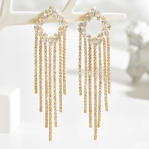 Close-up of golden tassel drop earrings featuring sparkling rhinestones on a white branch