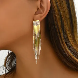 Macro shot of elegant long gold tassel earrings with shimmering white rhinestones