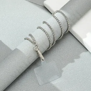 Long silver box chain phone strap with a clear attachment pad on a display stand