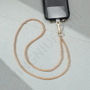 Detailed macro view of golden metallic crossbody phone chain with black case and pad