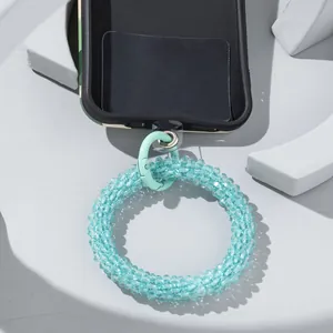 Detailed macro view showing blue beaded phone strap connected to transparent PVC patch