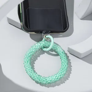 Light green glass bead phone wrist strap with metal clasp on modern white background
