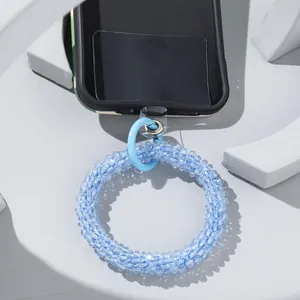 Close-up of light blue glass bead phone strap with transparent pad on white platform