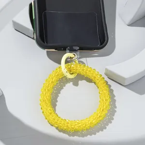 Macro shot of bright yellow beaded phone wrist strap with metal spring clasp and adapter