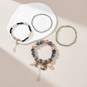 Close-up of Bohemian beaded bracelet set with moon and shell charms on a ceramic tray