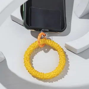 Detail of yellow beaded phone strap with orange spring ring buckle on camo phone case