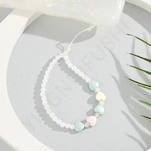 Close-up of pastel macaron heart beads and faux pearls on a stylish mobile phone lanyard