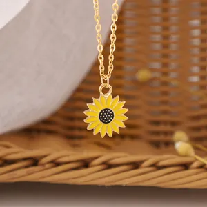 Golden necklace with yellow enamel sunflower pendant on a natural woven background