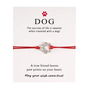Detail eines roten geflochtenen Pfoten-Armbands auf Geschenkkarte mit DOG-Schriftzug