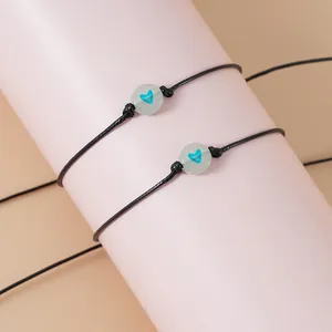 Detailopname van zwarte waxkoord armbanden met lichtgevende blauwe hartkralen op houder