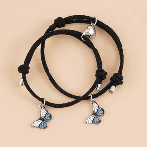 Detail von Paar-Armbändern mit Magnet-Herzverschluss und Schmetterling auf rosa Grund