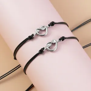 Vista macro di braccialetti regolabili in cordoncino nero con ciondoli a cuore in argento