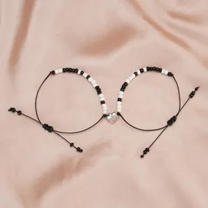 Magnetic heart bracelets for couples with black and white beads on satin background