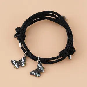 Detail von Herz-Magnetschließe und Schmetterlingsanhängern an schwarzen Armbändern