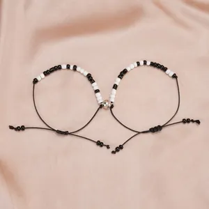 Close-up of heart-shaped magnetic couple bracelets with black and white beads on silk