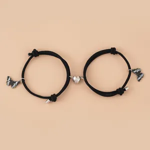 Detail von Magnet-Herzverschluss und Schmetterlingsanhängern an schwarzen Armbändern