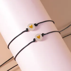 Detail van verstelbare zwarte geweven armbanden met hartkralen op een roze displaystand