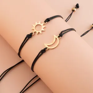 Detail of adjustable black woven cord bracelets with gold sun and moon pendants