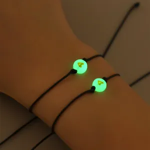 Detail van lichtgevende hartkralen op zwart gevlochten vriendschapsarmbanden in het donker