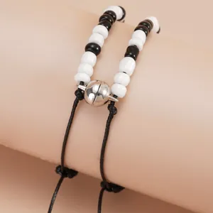 Detailed macro view of magnetic heart clasps connecting black and white beaded bracelets