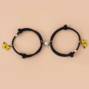 Detail der Herz-Magnetschließe an geflochtenen Paar-Armbändern mit gelben Schmetterlingen