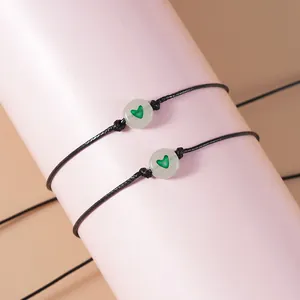 Detail van verstelbare zwarte geweven armbanden met lichtgevende groene hartkralen op houder