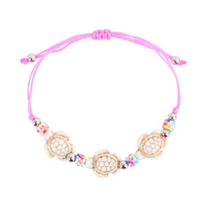 Detail of pink woven bracelet with turtle charms and colorful beads on white background