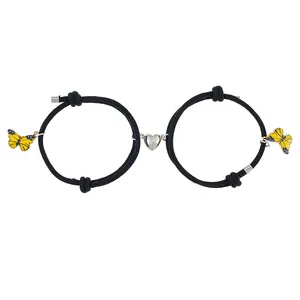 Detail der Magnet-Herz-Schmetterling-Armbänder mit schwarzen gewebten Kordeln in Gelb
