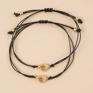 Vista dettagliata di braccialetti in corda nera intrecciata con nodi a cuore dorati